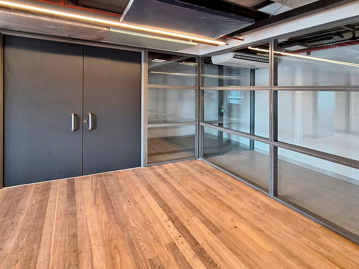 Divisão de ambiente grande com porta dupla na cor preta, com dois puxadores modernos prata. As divisórias no estilo grade, com suportes transversais e horizontais e vidros sem cor, acompanham a porta com encaixe perfeito.