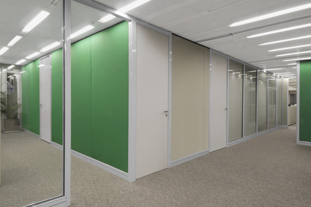 Ambiente corporativo com divisórias acústicas verdes combinadas com painéis de vidro fosco