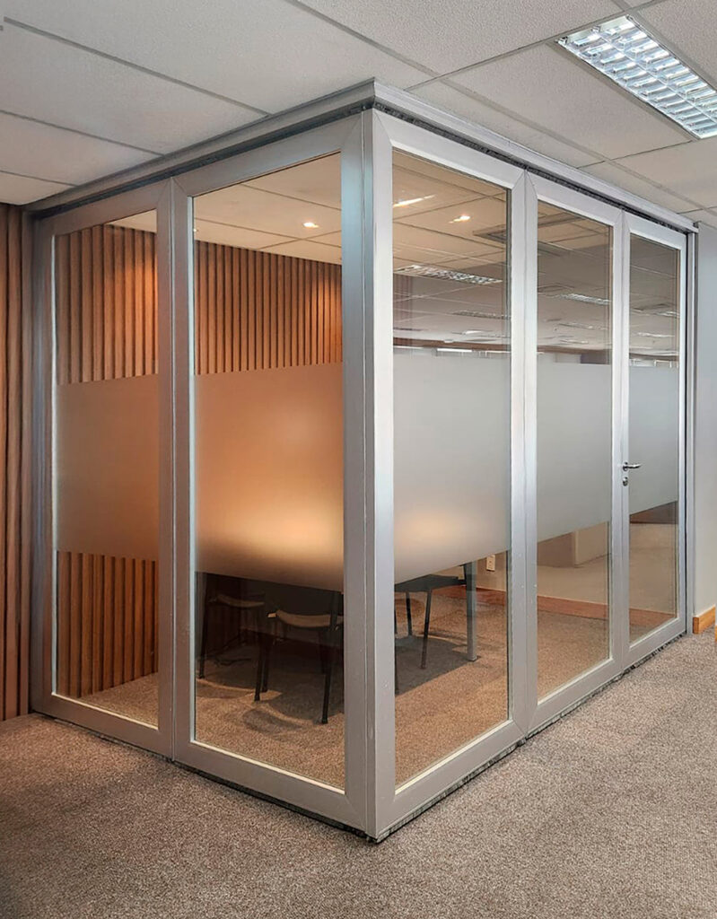 Sala corporativa com divisória retrátil 100 mm da Solid com vidro único e faixa fosca – solução flexível para ambientes moduláveis.